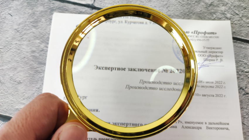 Фрагмент экспертного заключения под увеличительным стеклом в центре кадра