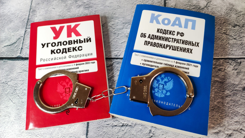 Книги УК РФ и КоАП с наручниками на фоне плитки