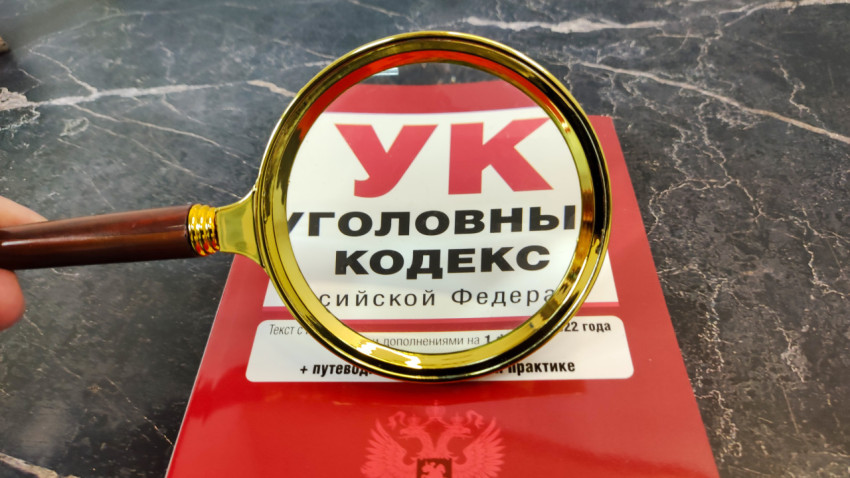 Обложка Уголовного кодекса под увеличительным стеклом на мраморе