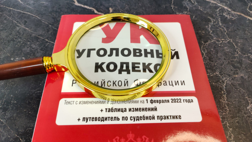 Уголовный кодекс РФ под увеличительным стеклом на мраморной поверхности