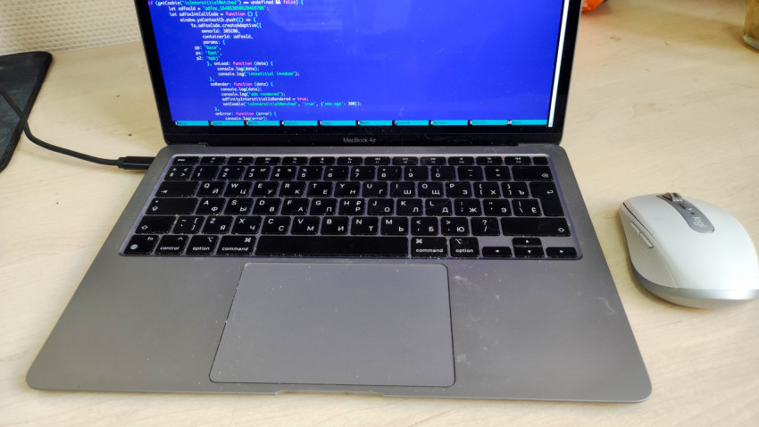 MacBook Air с кодом и беспроводной мышью на офисном столе