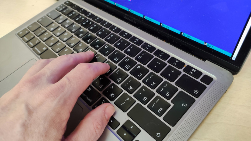 Рука на клавиатуре ноутбука MacBook Air с кодом на экране