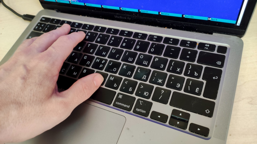 Пальцы на клавиатуре ноутбука MacBook Air на светлом столе
