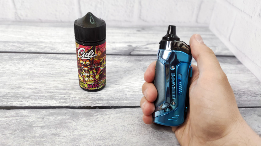 Вейп GeekVape в руке и жидкость Cult Lemon Killer на столе