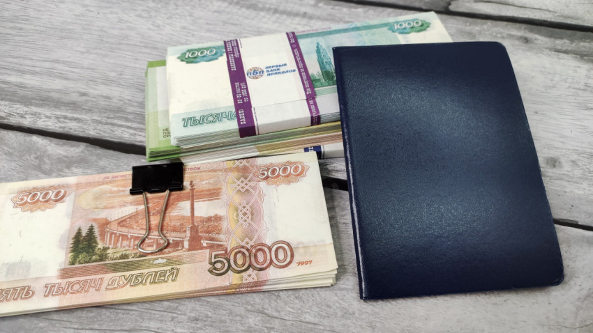 Пачки российских банкнот и синий блокнот на деревянном фоне