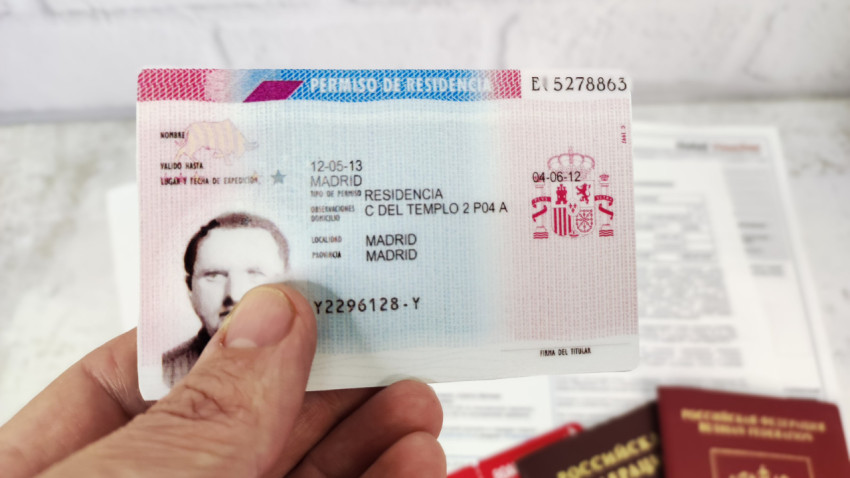 Испанский вид на жительство в руках с паспортами РФ на фоне