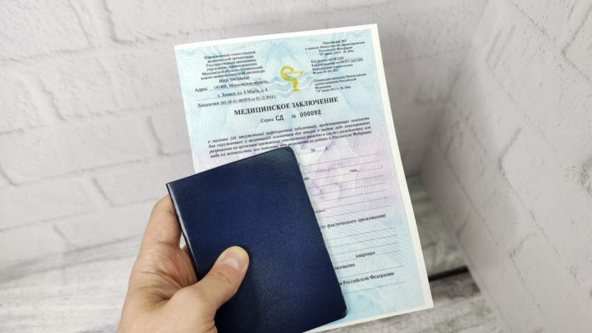 Медицинское заключение в руке с синей обложкой паспорта