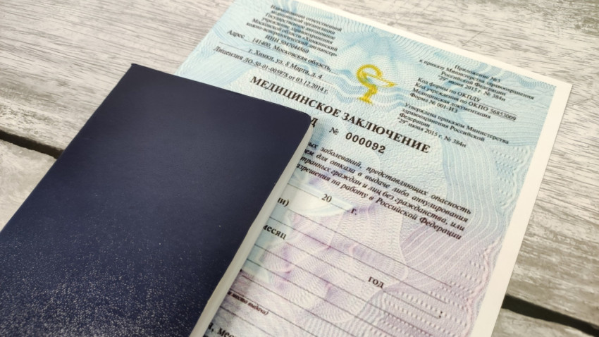 Медицинское заключение с обложкой синего цвета на деревянной поверхности