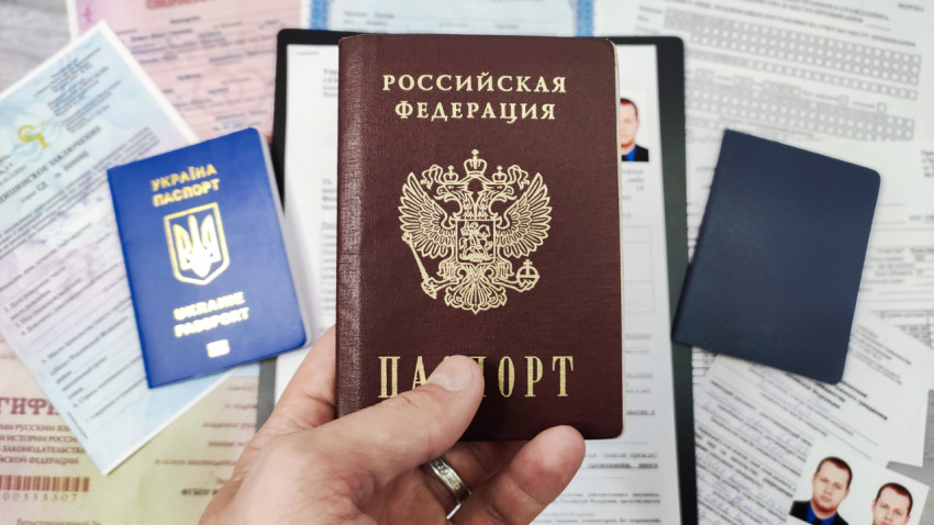 Паспорт Российской Федерации в руке на фоне миграционных документов