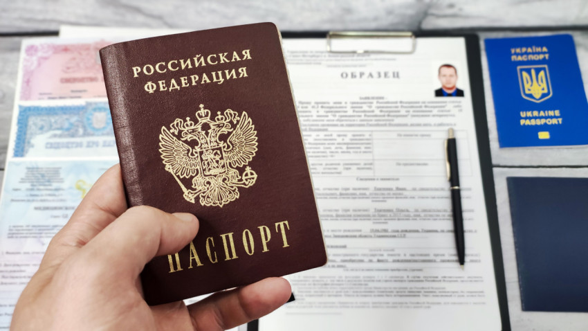 Паспорт гражданина РФ в руке на фоне документов для получения гражданства