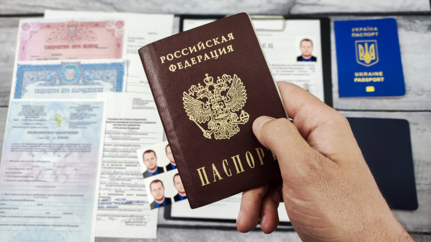 Паспорт РФ в руке на фоне украинских документов и заявления на гражданство