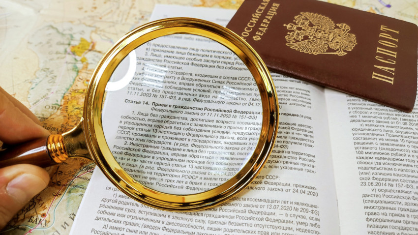 Изучение текста закона о гражданстве с лупой и паспортом России