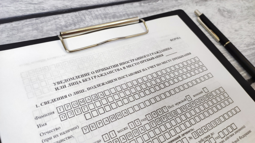 Заполненный бланк уведомления о прибытии на планшете с ручкой