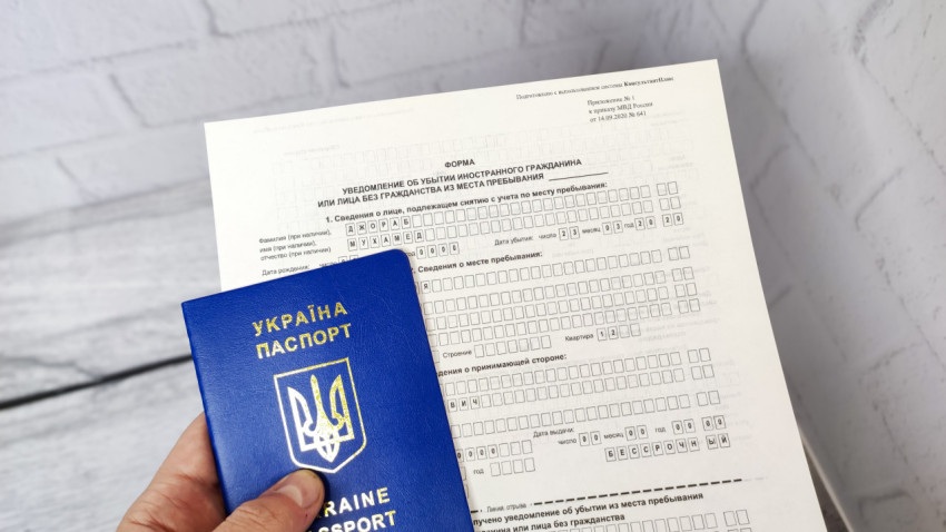 Паспорт Украины в руке на фоне бланка уведомления о выбытии