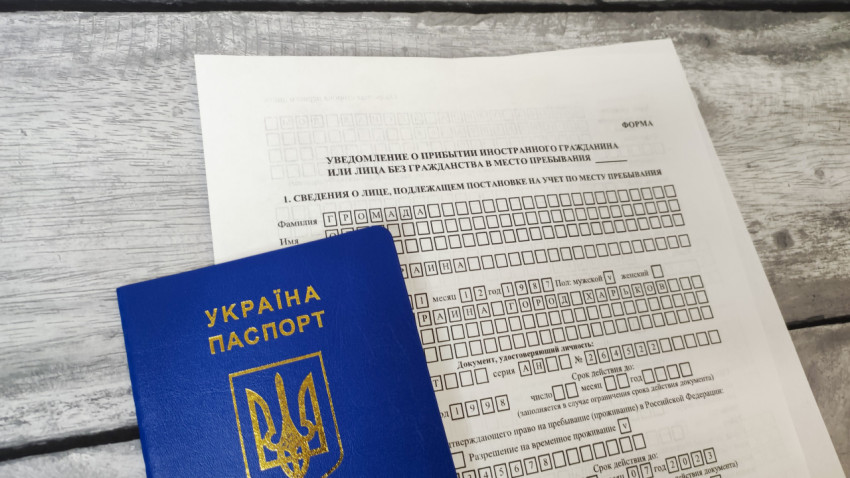 Паспорт Украины на фоне бланка уведомления о прибытии иностранного гражданина
