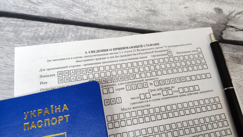 Бланк уведомления о прибытии иностранного гражданина с паспортом Украины и ручкой