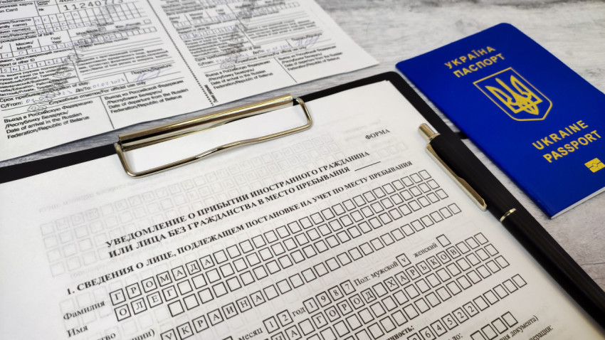 Паспорт Украины и бланк уведомления о прибытии на планшете с ручкой