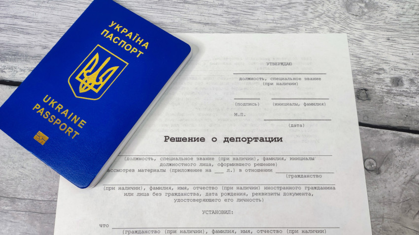 Паспорт Украины и решение о депортации на деревянной поверхности
