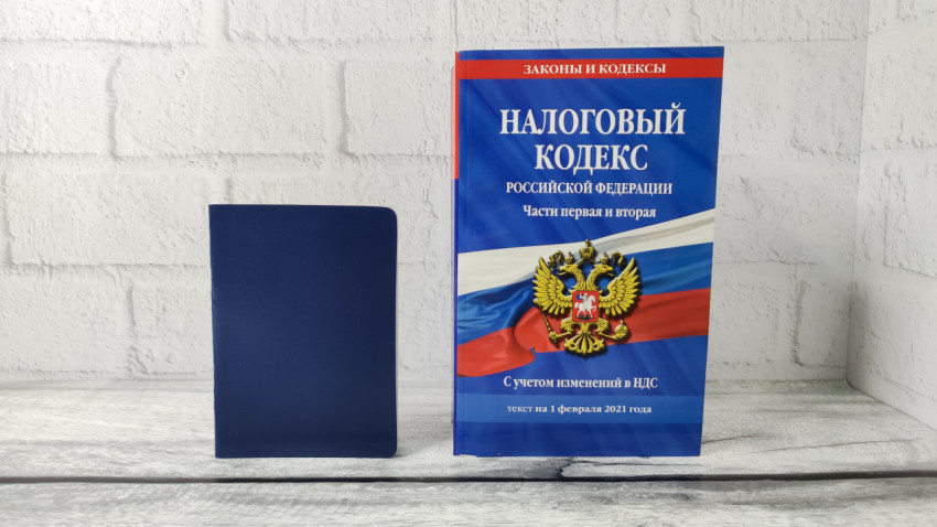 Налоговый кодекс РФ и синяя обложка для документов на фоне светлой стены