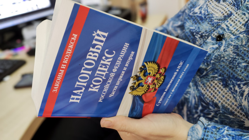 Налоговый кодекс РФ в руках человека в синей рубашке