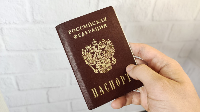 Внутренний паспорт РФ в руке на фоне белой стены