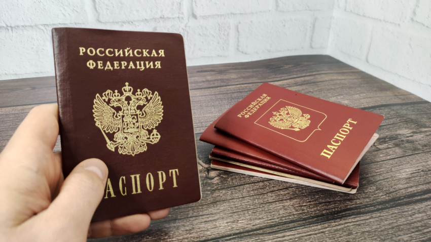 Российский паспорт в руке на фоне стопки загранпаспортов