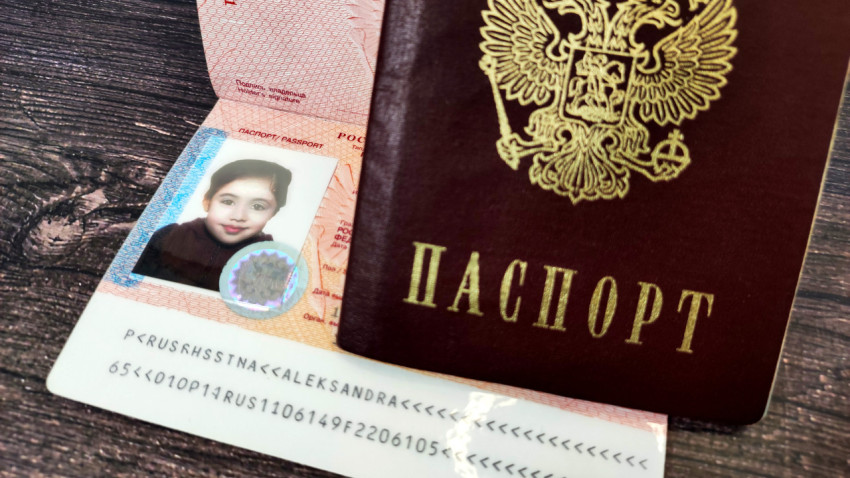 Заграничный паспорт России с фотографией ребёнка, частично прикрытый внутренним паспортом