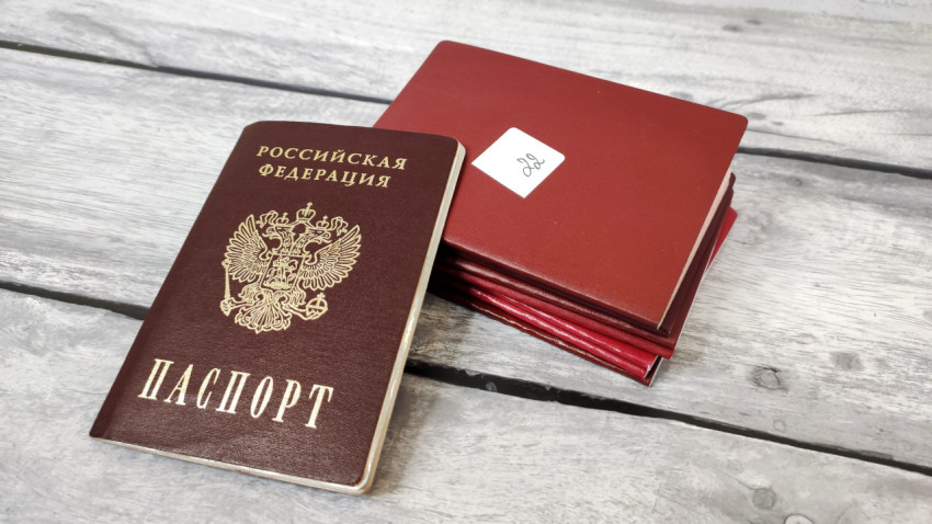 Паспорт РФ и красные обложки на деревянной поверхности