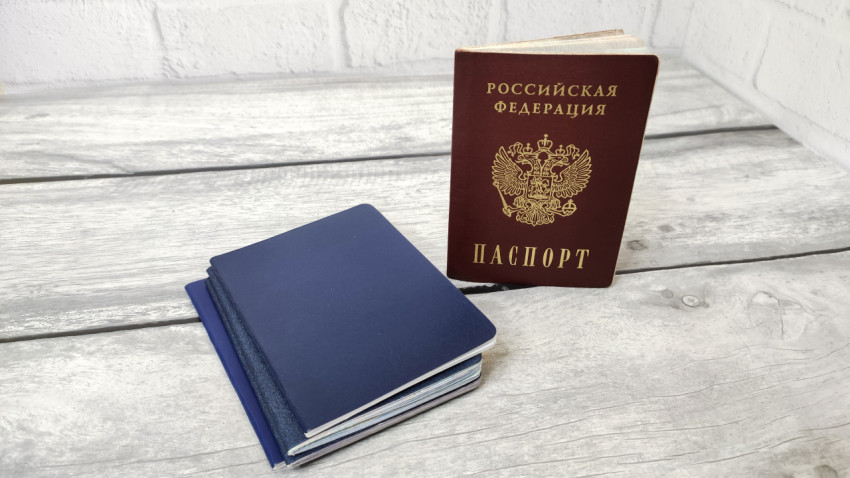 Паспорт России и стопка синих обложек на столе