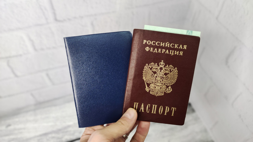 Рука держит паспорт России и синюю обложку