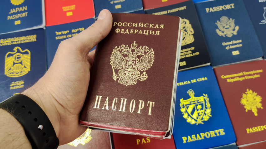 Паспорт гражданина России в руке на фоне паспортов разных стран