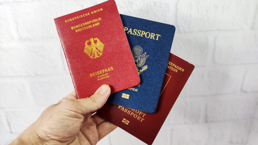 Паспорта Германии, США и России, удерживаемые в руке
