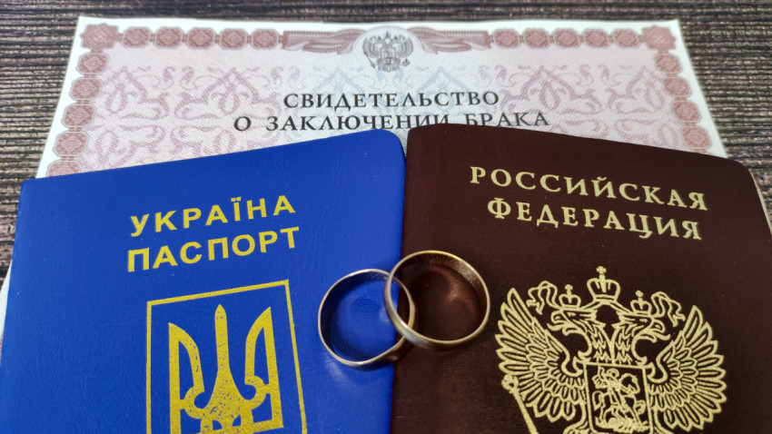 Паспорта России и Украины с кольцами на фоне свидетельства о браке