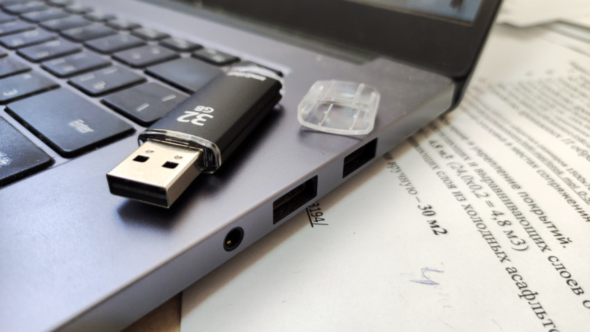 USB-накопитель и ноутбук на фоне печатного документа