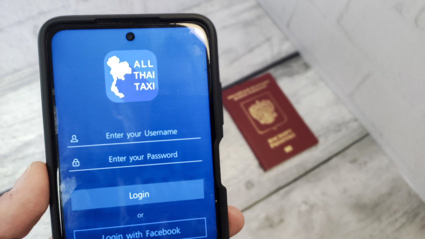 Приложение ALL THAI TAXI на экране смартфона с загранпаспортом РФ на заднем плане