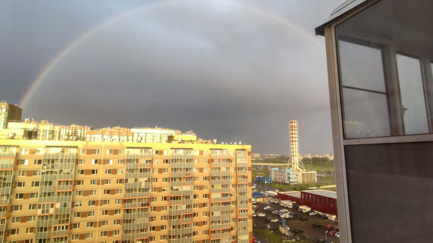 Радуга над новостройками и городской застройкой