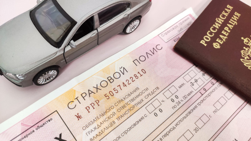 Российский страховой полис и паспорт рядом с моделью автомобиля