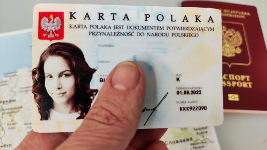 Карта Поляка в руке на фоне карты и паспорта