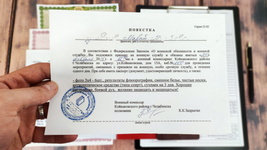 Повестка в военкомат с печатью и подписью на фоне документов