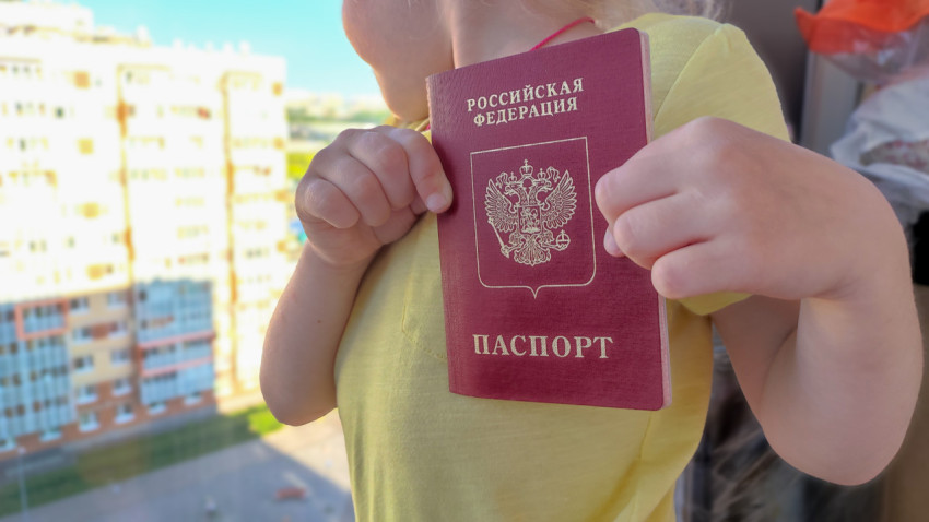 Ребенок с загранпаспортом РФ на фоне жилых домов