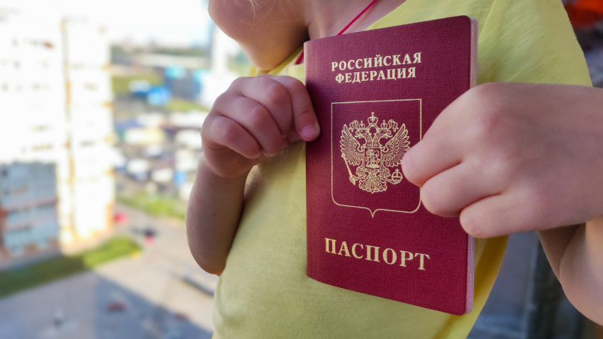 Загранпаспорт РФ в руках ребенка на фоне города