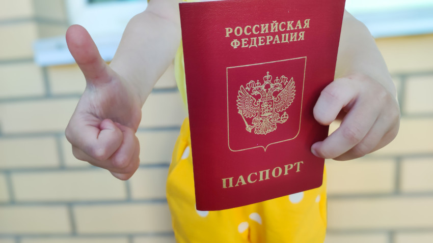 Ребенок держит загранпаспорт РФ и показывает жест «палец вверх»