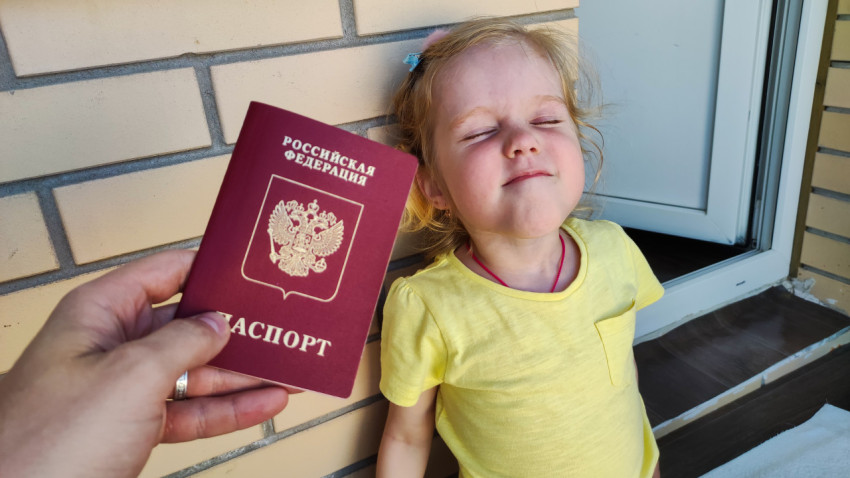 Ребенок и загранпаспорт РФ на фоне кирпичной стены