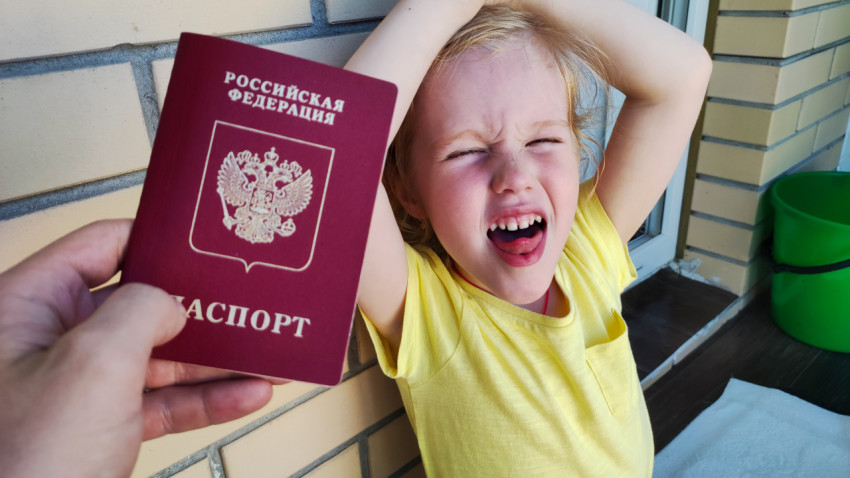 Загранпаспорт РФ и ребенок в желтой одежде на фоне стены