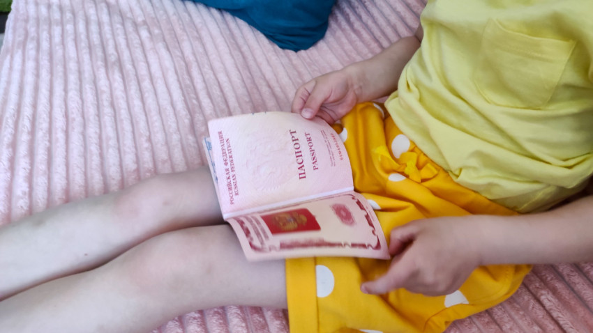 Девочка держит загранпаспорт РФ на коленях