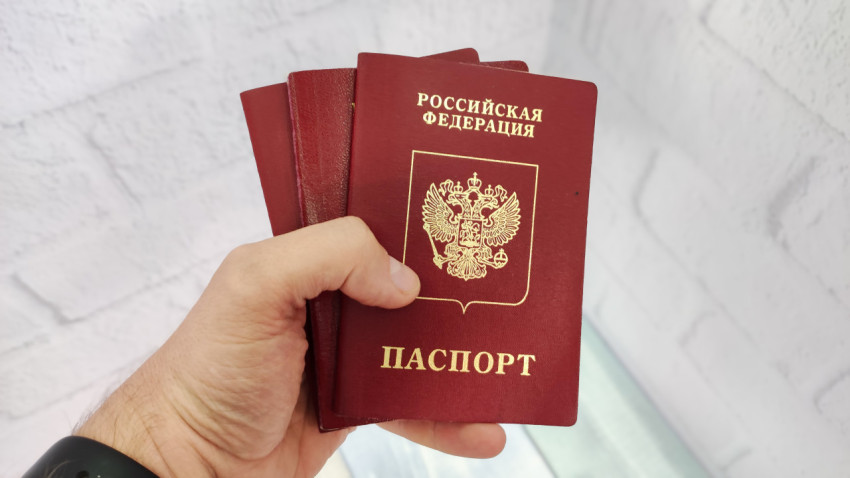 Загранпаспорта в руке на фоне белой стены