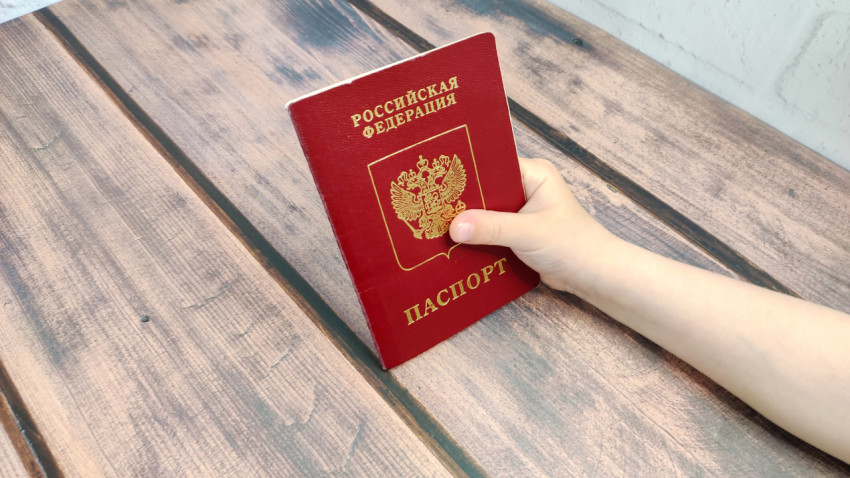 Загранпаспорт России в руке ребёнка на деревянной поверхности