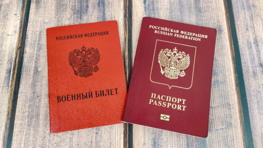 Военный билет и загранпаспорт России рядом на деревянной поверхности