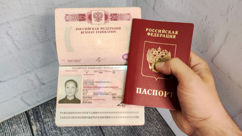 Загранпаспорт Российской Федерации в руке раскрытый на странице с фото