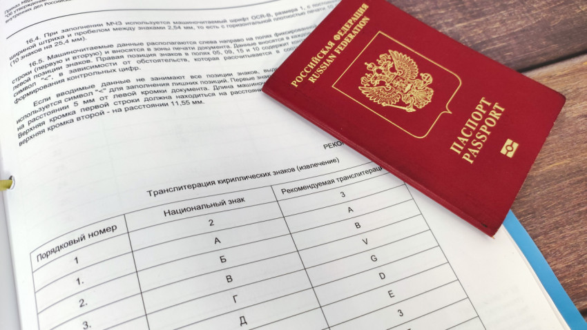 Заграничный паспорт Российской Федерации на фоне документа с таблицей транслитерации